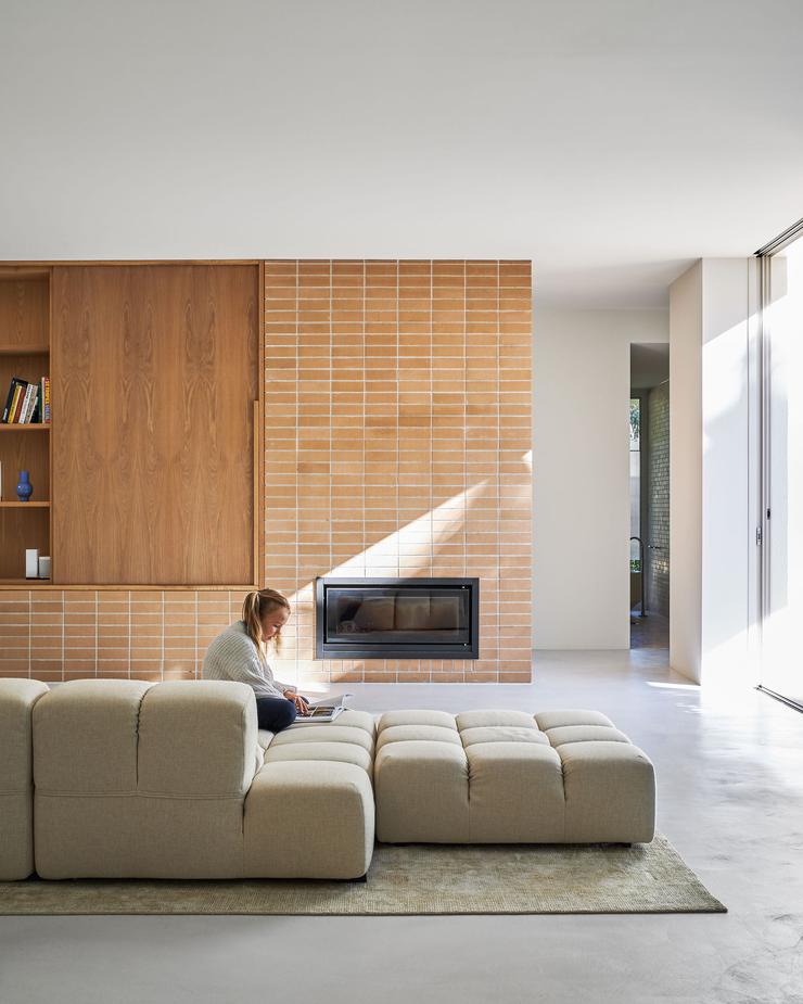 Modern architect designed house microcement floors cream couch, joinery unit with oak veneer doors, face brick and inset fireplace